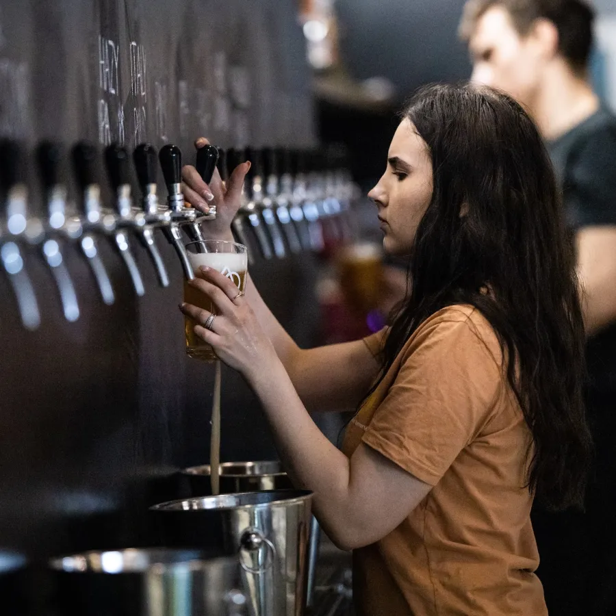 Young woman pouring beer from tap