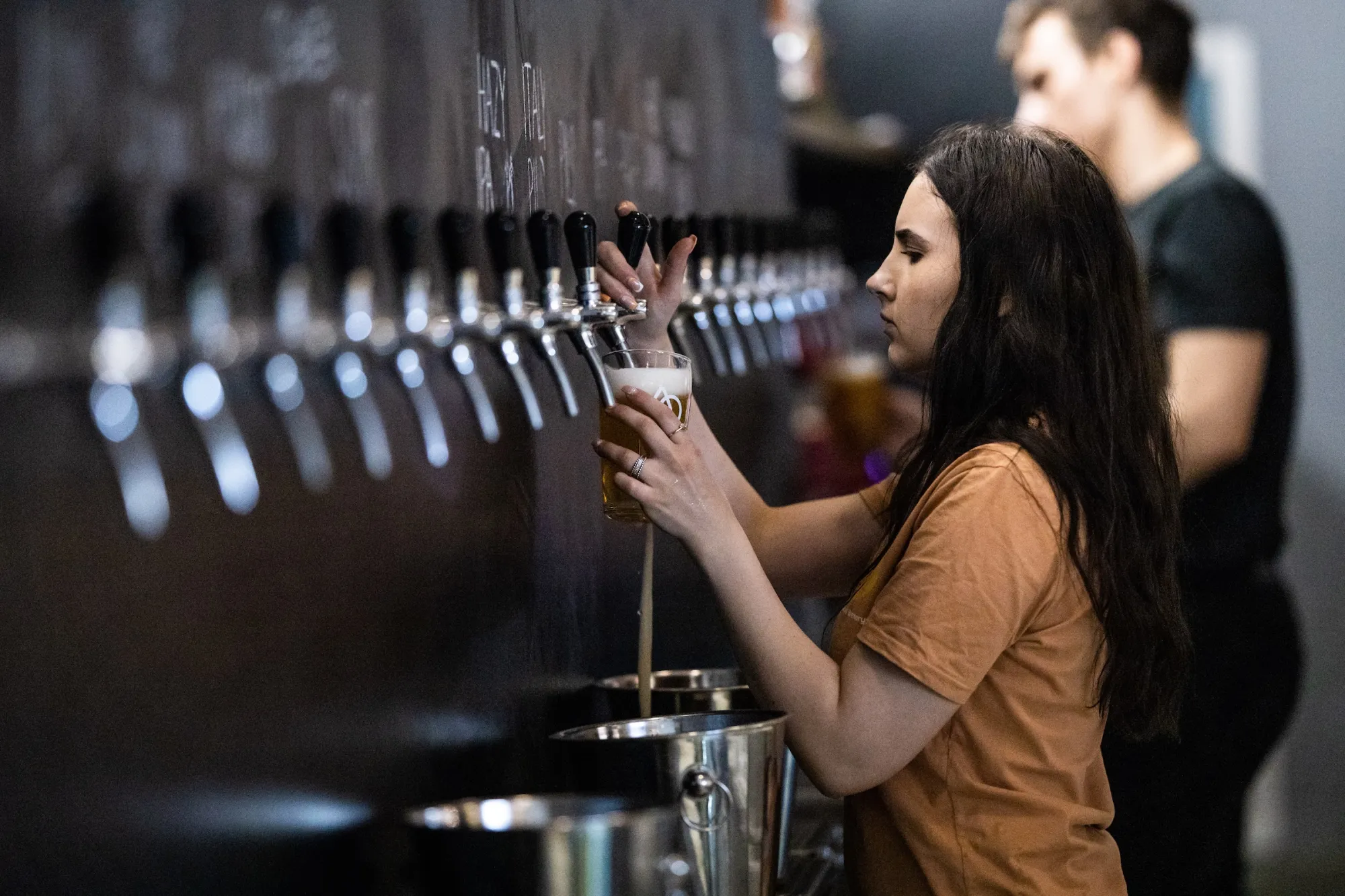 Young woman pouring beer from tap